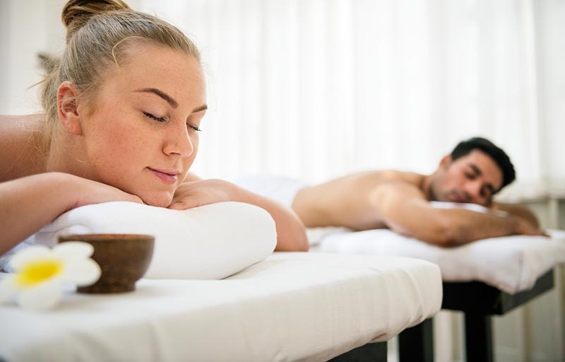 A male and female couple lying down on massage tables waiting for their couples massage to start