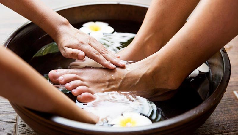 A pair of feet receiving a foot massage in a bowl of water