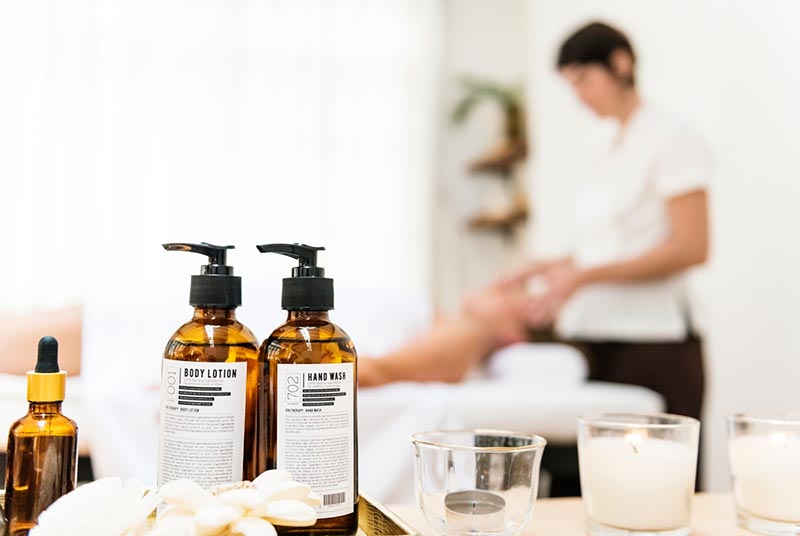 Massage oils and candles with lady lying on back on massage bed receiving a head massage