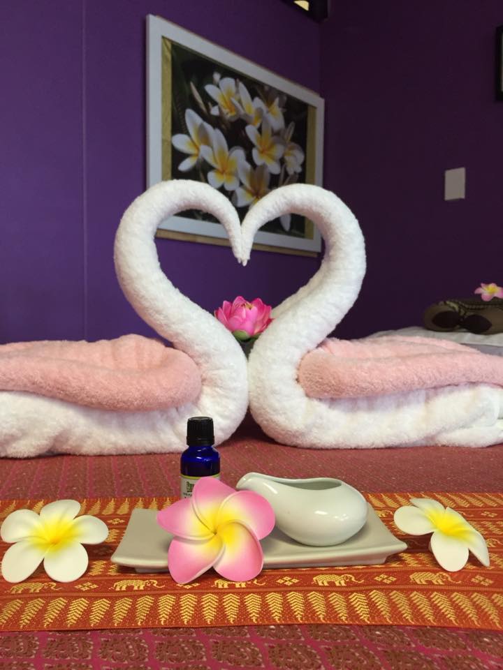 Towels shaped into swans forming a heart with their beaks on a massage table inside Sawaddee